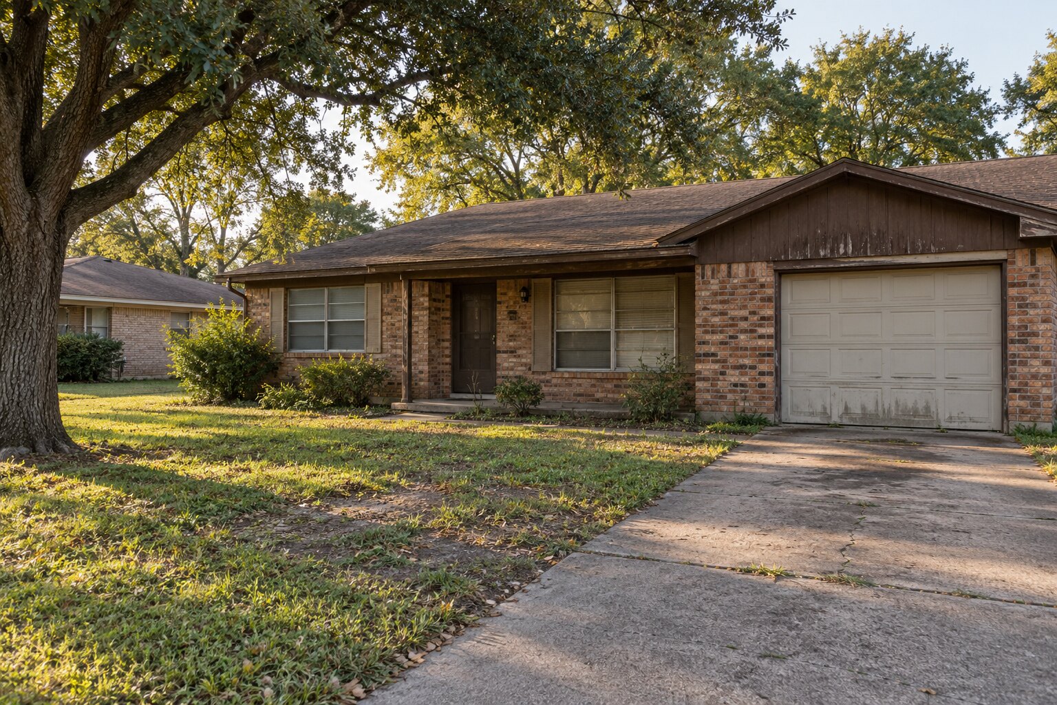 An older brick ranch with a worn driveway and a patchy lawn